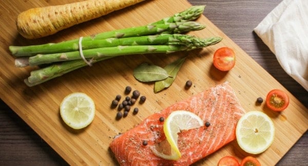 Salmon, lemon and asparagus on a chopping board.