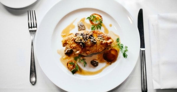 A white plate with chicken, sauce, and garnishes.