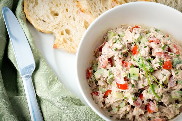 Tuna salad in a white bowl next to bread