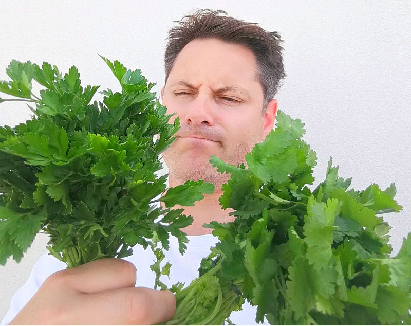 A man holding bunches of parsley and cilantro