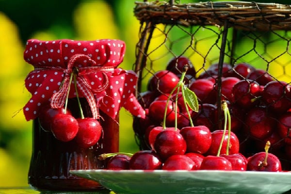 A jar of cherry conserve and fresh cherries