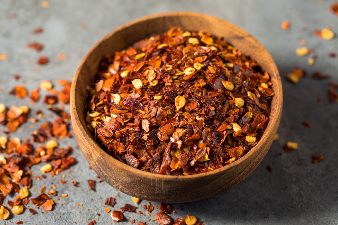 Fresh Red Pepper Flakes In Small Wooden Bowl