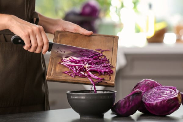 Scraping chopped red cabbage into a bowl