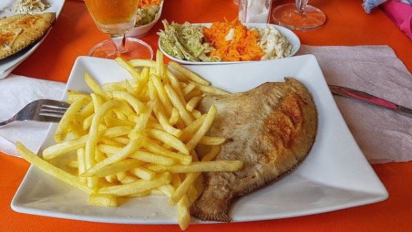 Flounder and chips on a white plate.
