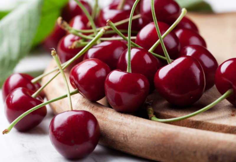 Fresh cherries scattered on a board.