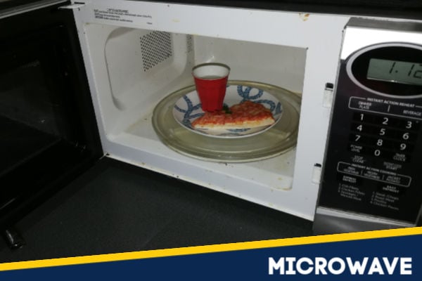 A slice of pizza reheating in the microwave