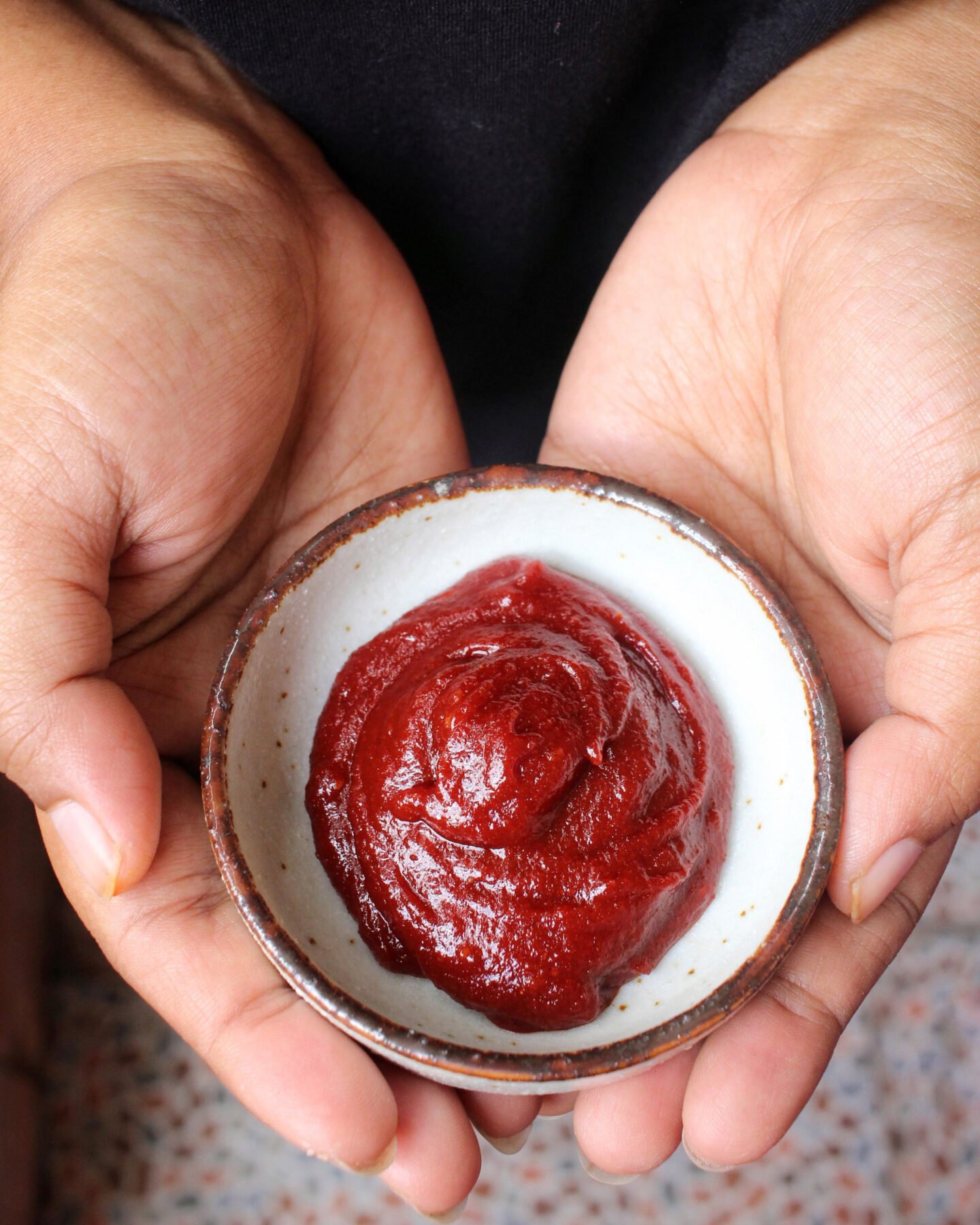 hands holding bowl of korean chili paste