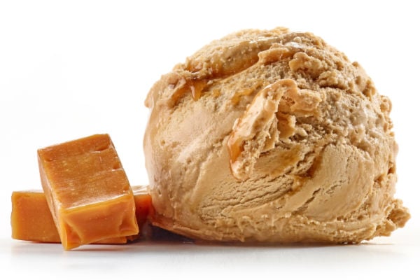 Caramel ice cream scoop next to pieces of caramel