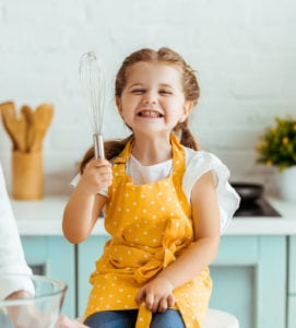 Girl holding whisk in the kitchen