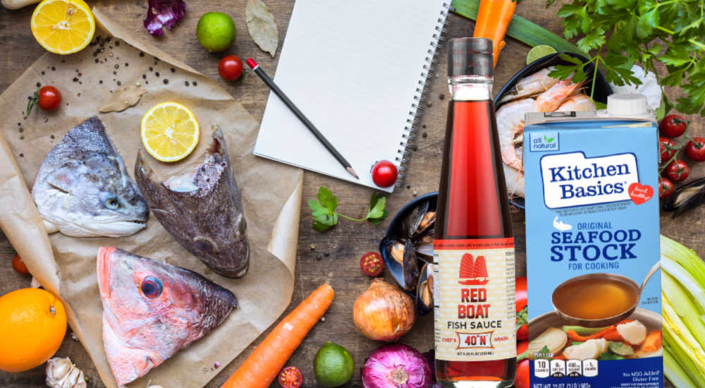 Fish stock and fish sauce next to a bench covered with ingredients