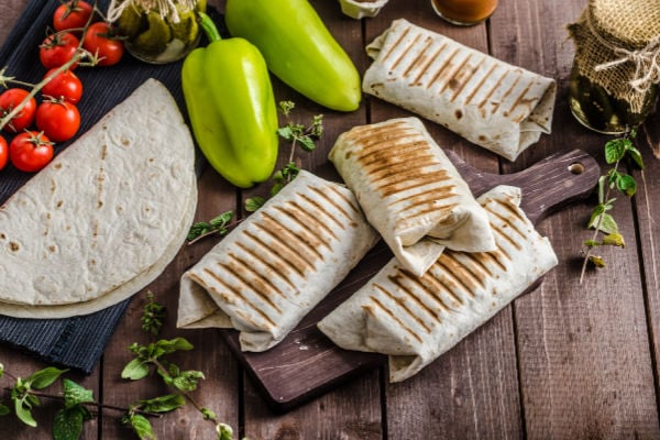 Breakfast burritos on a table with fresh vegetables