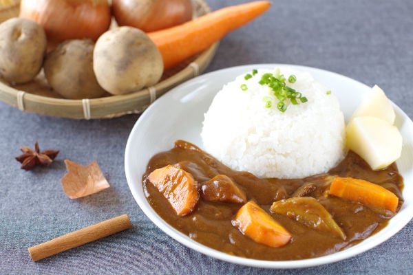 A bowl of curry rice next to fresh vegetables