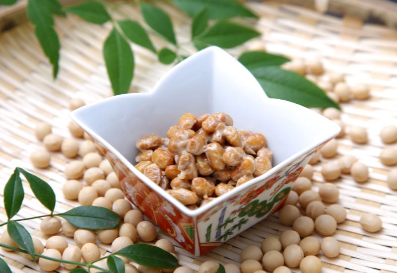 A bowl of natto next to scattered soybeans
