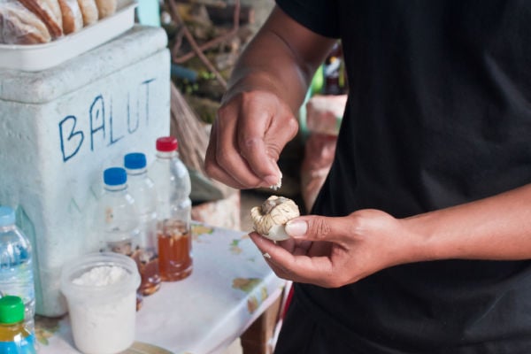 A street vendor seasoning balut.
