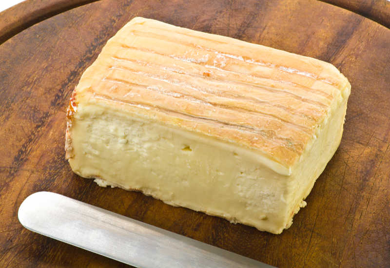 A block of taleggio cheese on a board