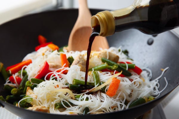 Soy sauce tipped onto rice nodles and vegetables