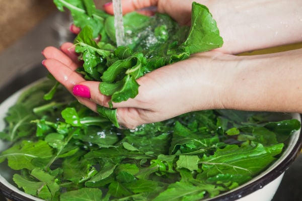 Rinsing arugula under a tap