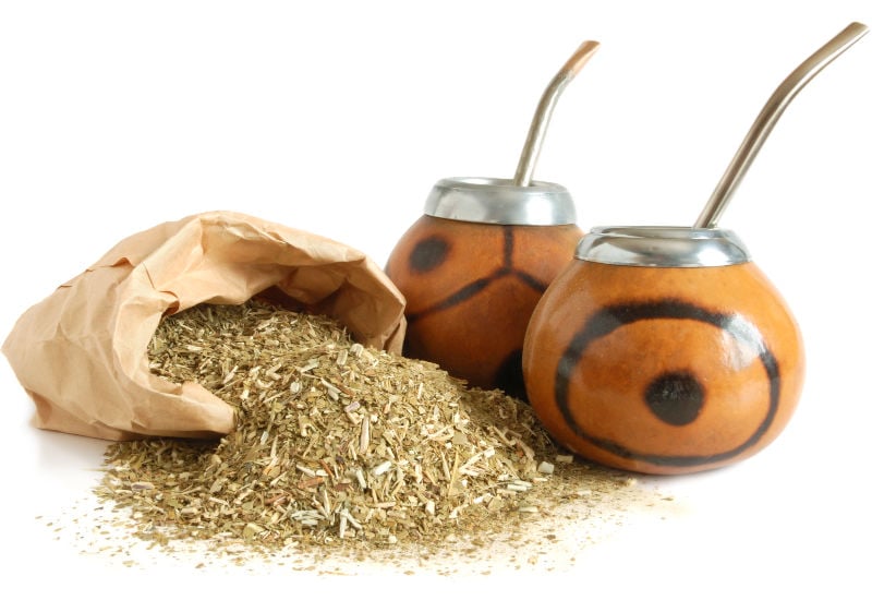 Dried yerba mate next to two gourds