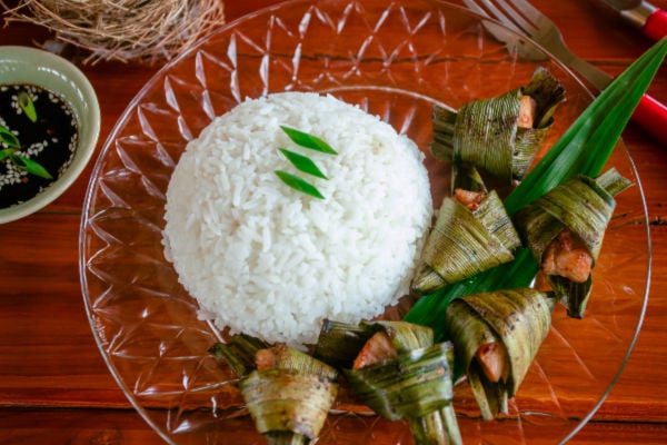 Pandan leaves wrapped arounf chicken on a plate with rice
