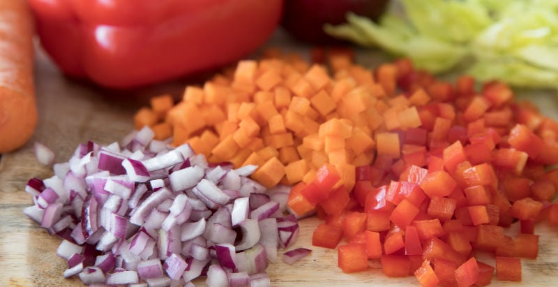 Diced red onion, carrot and bell pepper on a chopping board