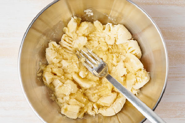 A bowl of mashed bananas and a fork