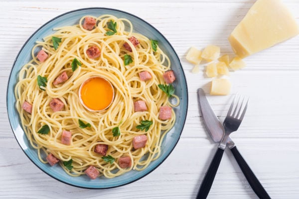 A bowl of Spaghetti alla carbonara next to cutlery
