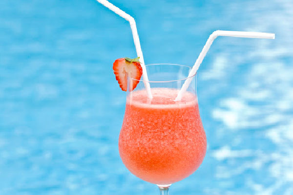 A glass of Strawberry Daiquiri next to a pool