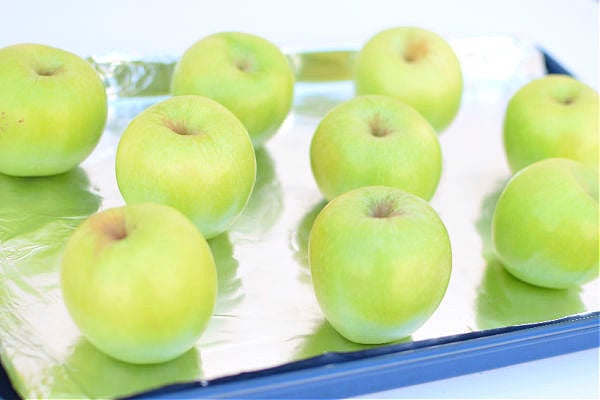 Unpeeled apples on a lined baking tray