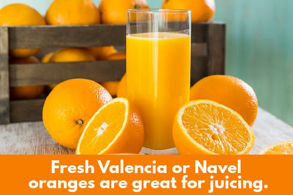 Fresh oranges next to a glass of juice