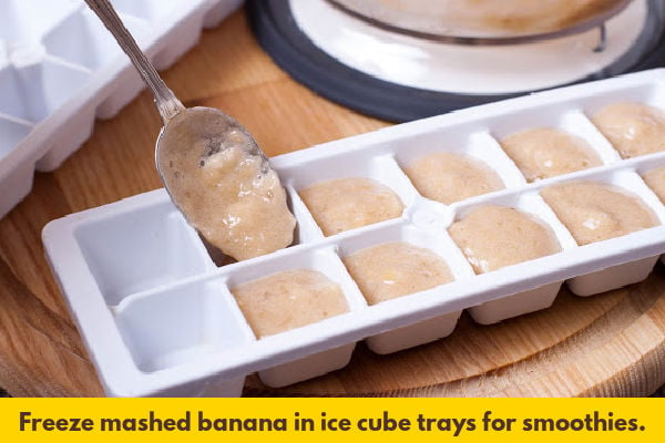 Spooning mashed banana into an ice cube tray ready to freeze