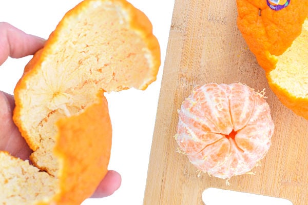 A hand holding sumo citrus peel next to a peeled fruit
