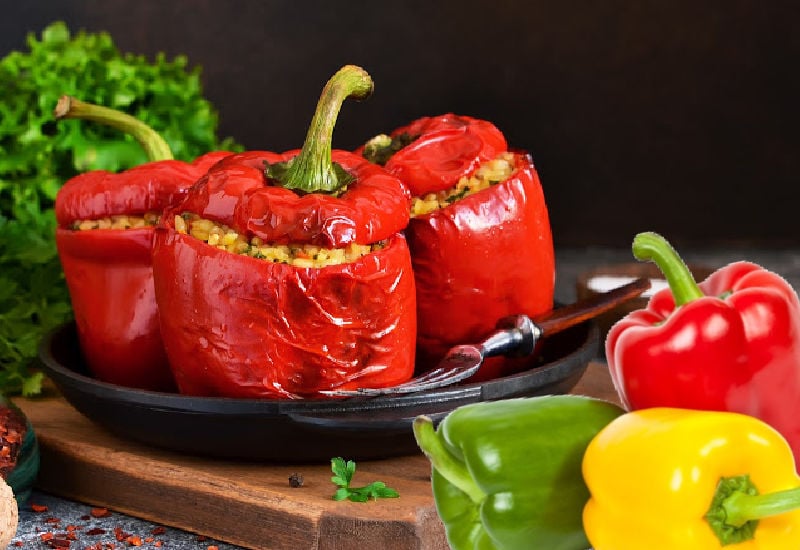 Various colored bell peppers next to stuffed peppers