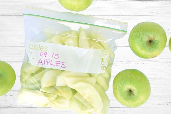 Green apples in a bag on a white wooden background.