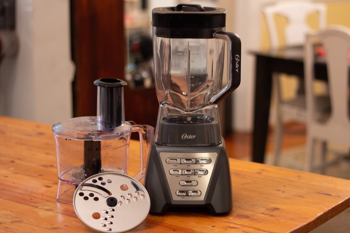 The Oster 1200 blender food processor on a countertop with all it's parts