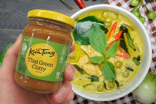 Holding a jar of green curry sauce next to a bowl of green curry