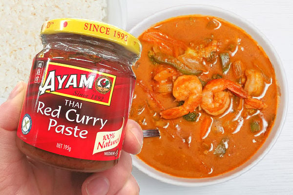 Holding a jar of red curry paste next to a bowl of curry