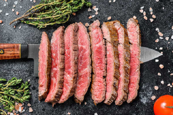 Flank steak in slices laying on a knife
