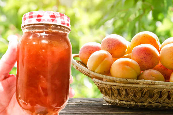 Holding a jar of apricot jam next to fresh fruit