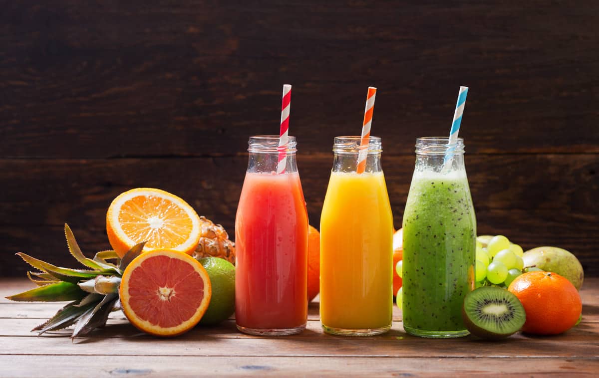 bottles of fruit juice and smoothie with fresh fruits