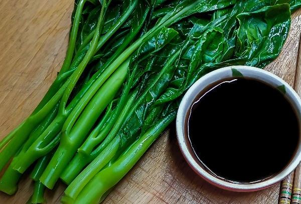 Gai lan on a chopping board with oyster sauce