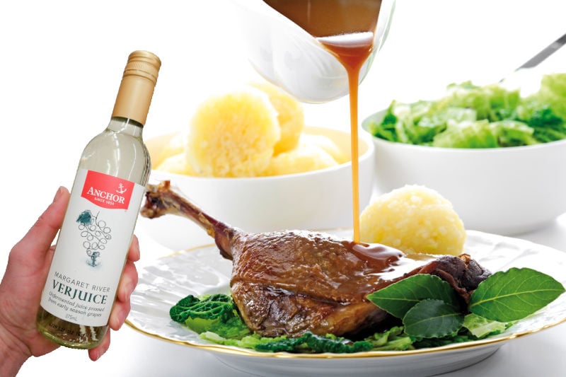 A bottle of verjuice next to a meat dish and sauce