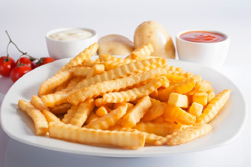 Cooked fries on a plate next to condiments