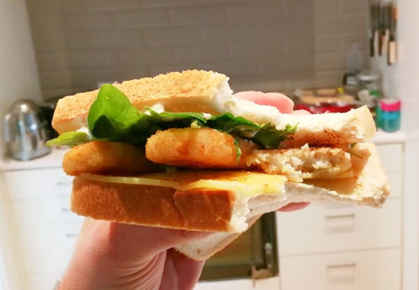 Holding a fish finger sandwich in the kitchen