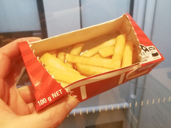 Holding cooked microwave fries box in the kitchen