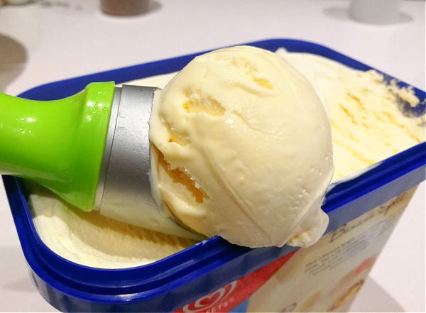 Scooping microwaved ice cream from a large tub