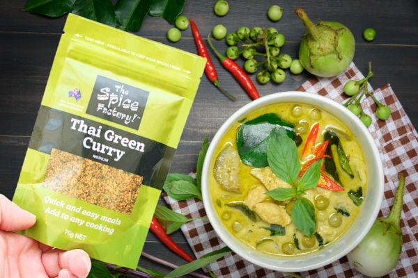 Holding a sachet of spices next to a bowl of Thai green curry