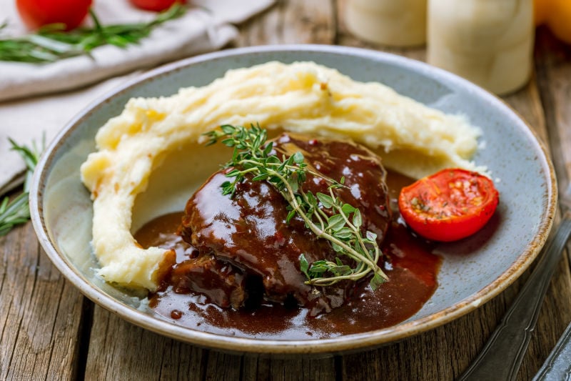 Beef Cheeks on a plate with mashed potatoes and herbs