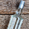 Bottle of 80-proof spirits lying on wooden boards