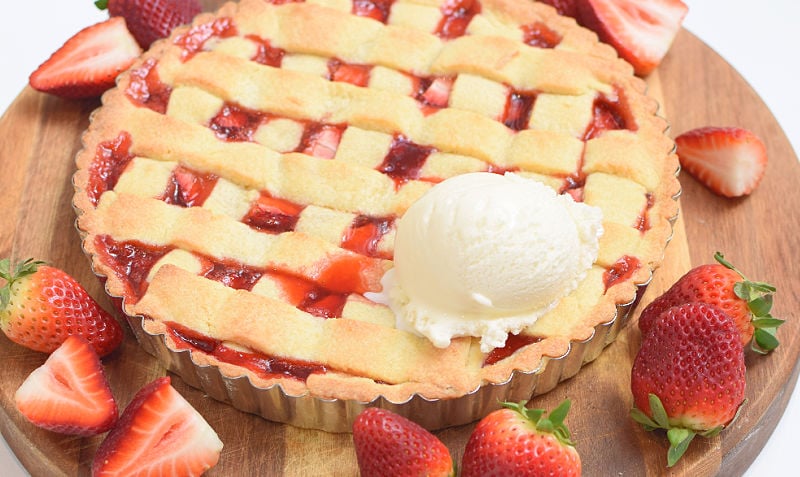 Strawberry crostata next to fresh strawberries and a scoop of ice cream