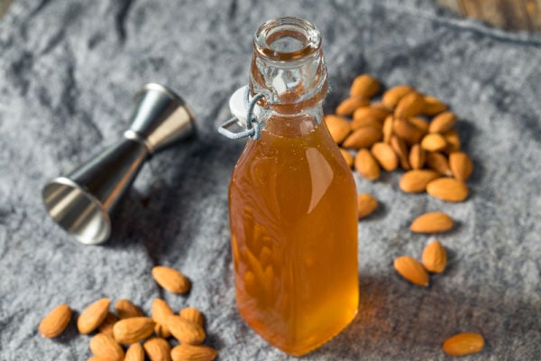 A bottle of homemade orgeat next to fresh almonds